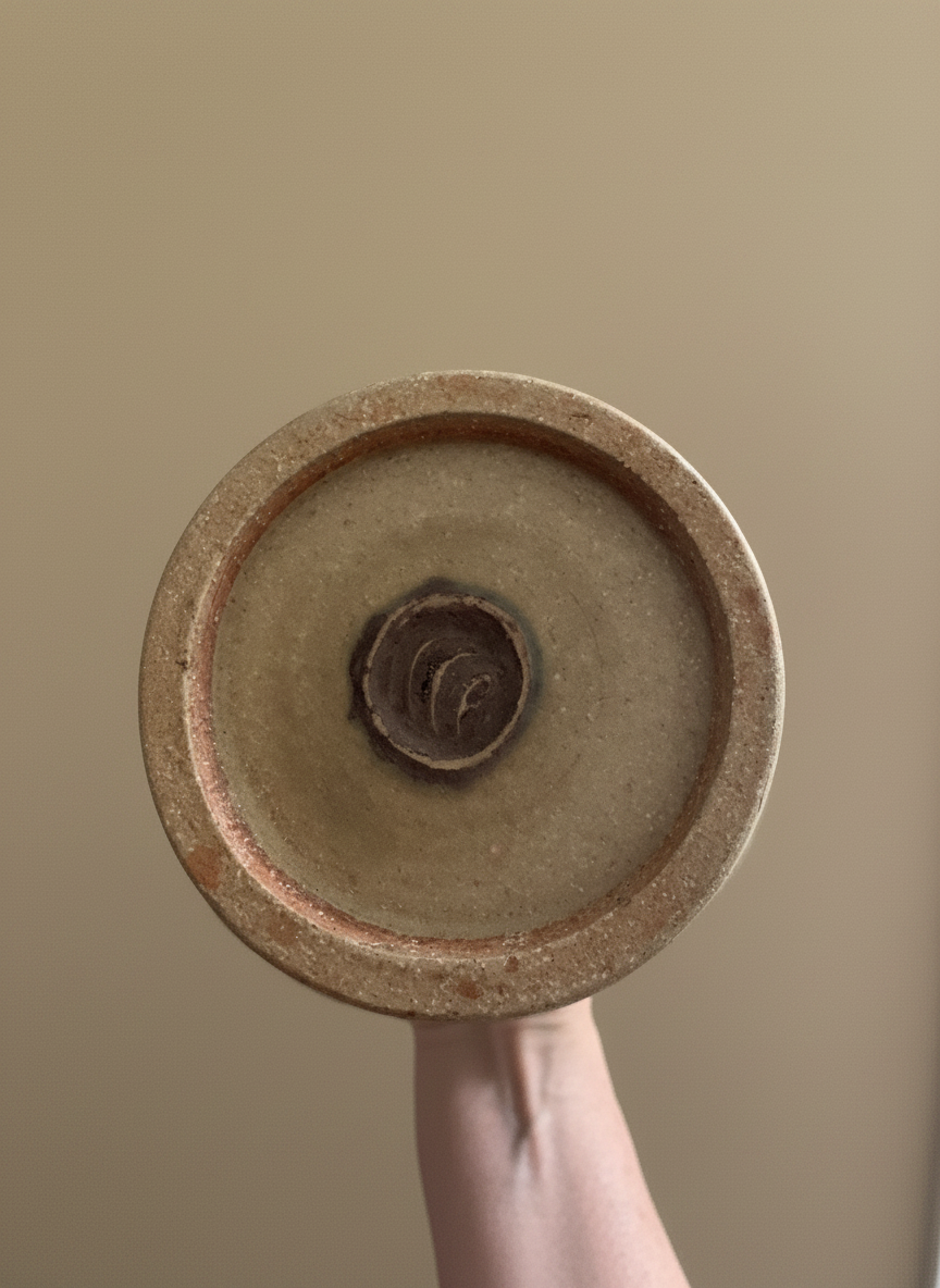 stamped base of a vase by chris carter with a hand holding the vase