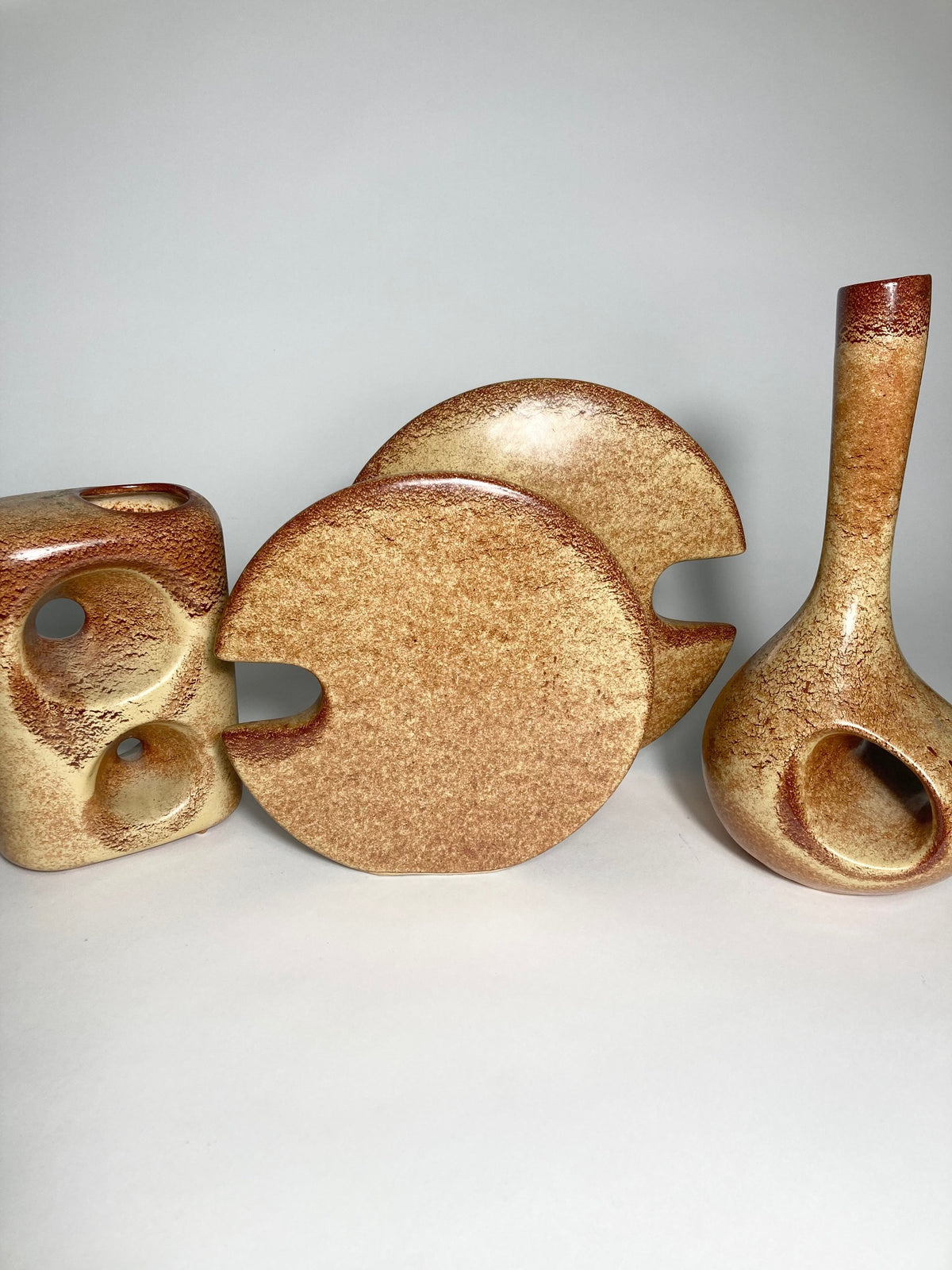 Set of ceramic bertoncello pieces with brown glaze on a light gray studio background