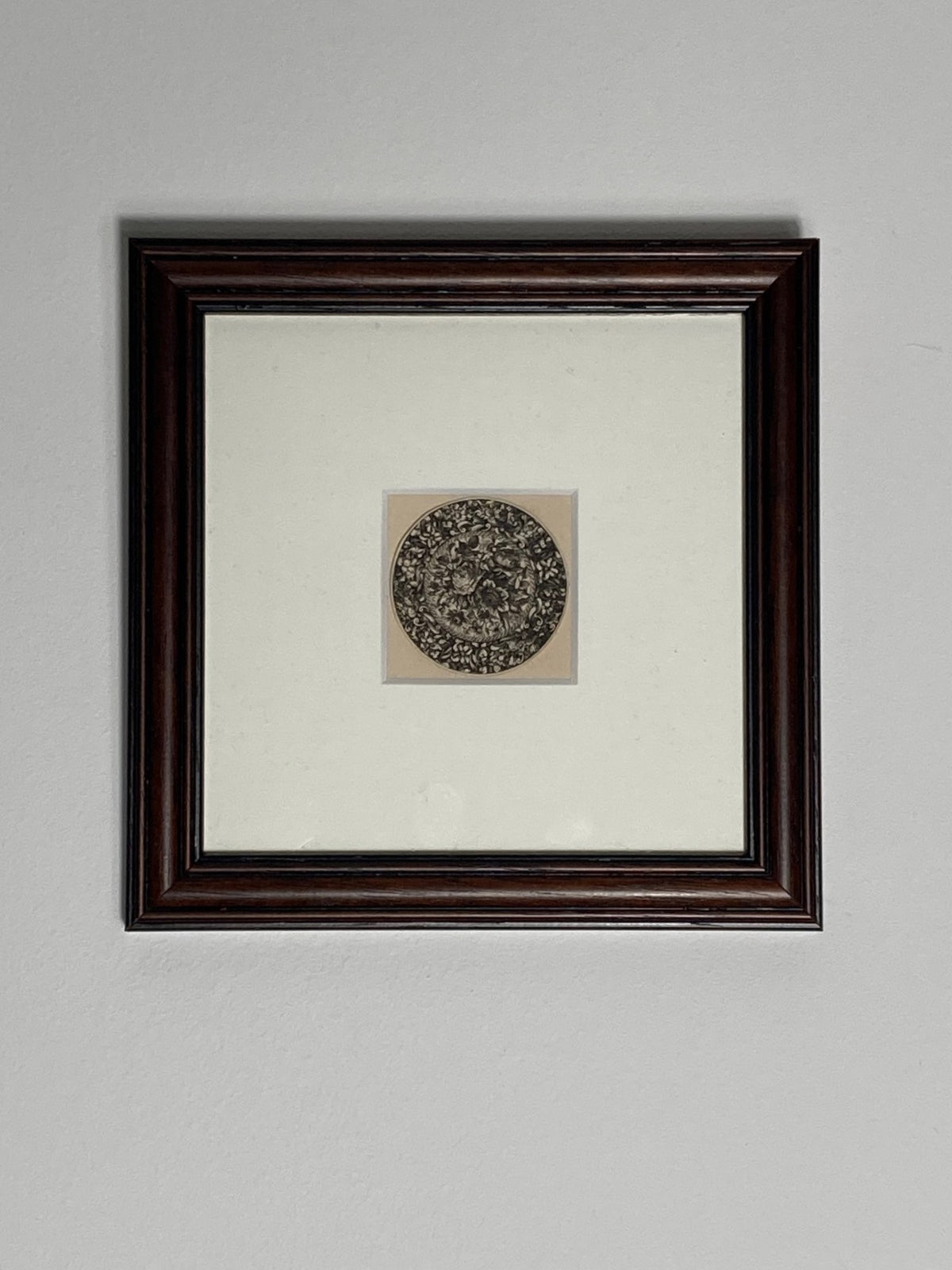 Framed artwork with a circular design on a plain background