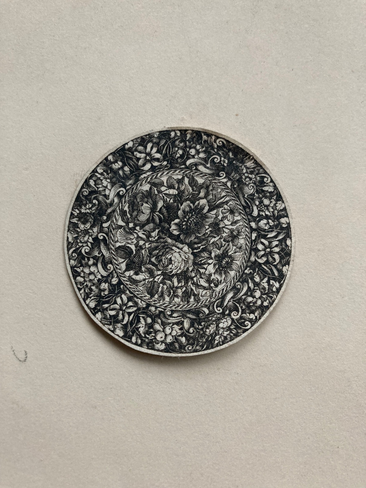 Decorative round object with floral and leaf patterns on a beige background
