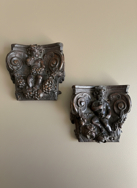 A pair of wood carvings on a taupe wall 