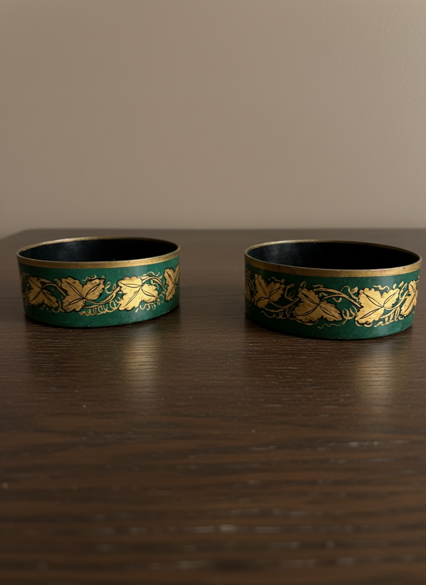 pair of toleware wine coasters in green and gold on a wooden table against a taupe wall