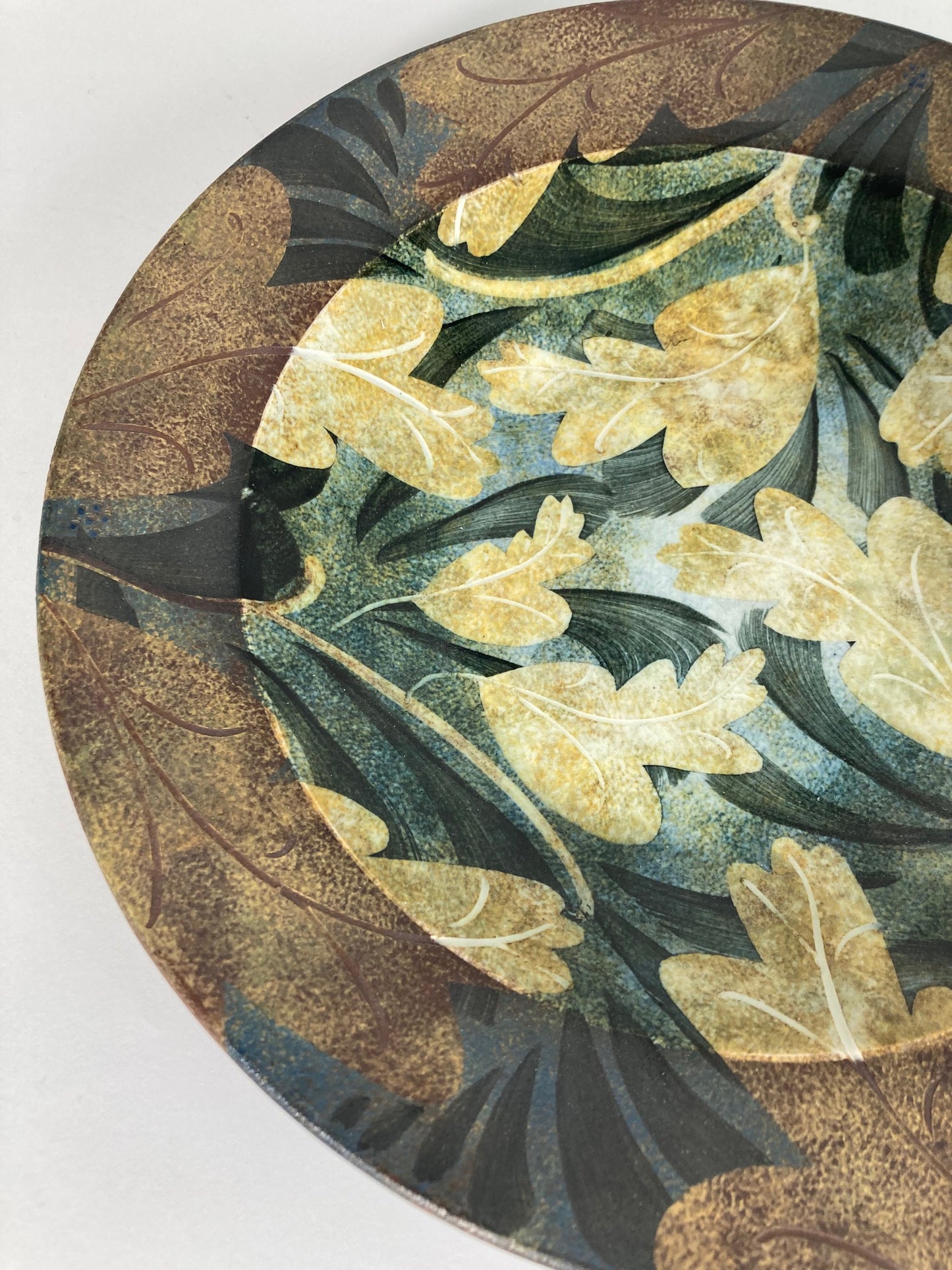 A highly decorative plate by Ralph Jandrell with a green and brown pattern and mixed glaze - close up image