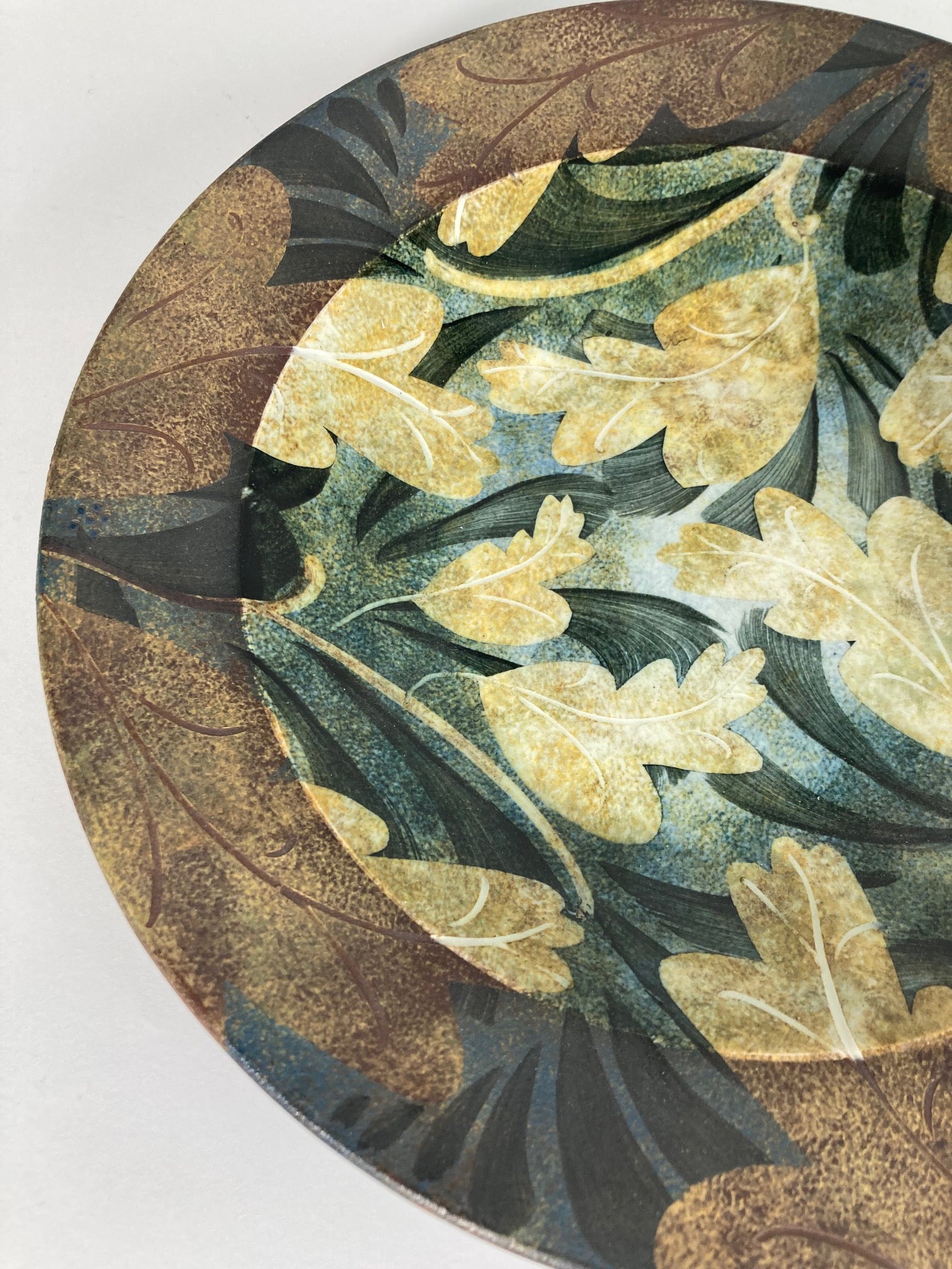 A highly decorative plate by Ralph Jandrell with a green and brown pattern and mixed glaze - close up image