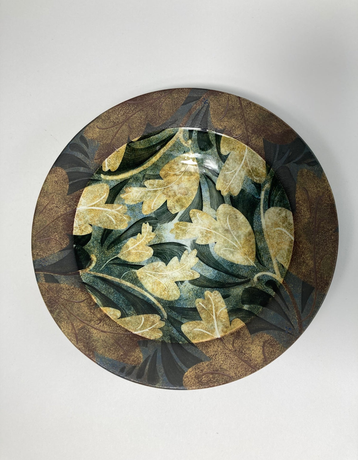 A highly decorative plate by Ralph Jandrell with a green and brown pattern and mixed glaze.